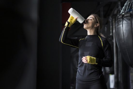 side-view-female-boxer-drinking-water-from-flask